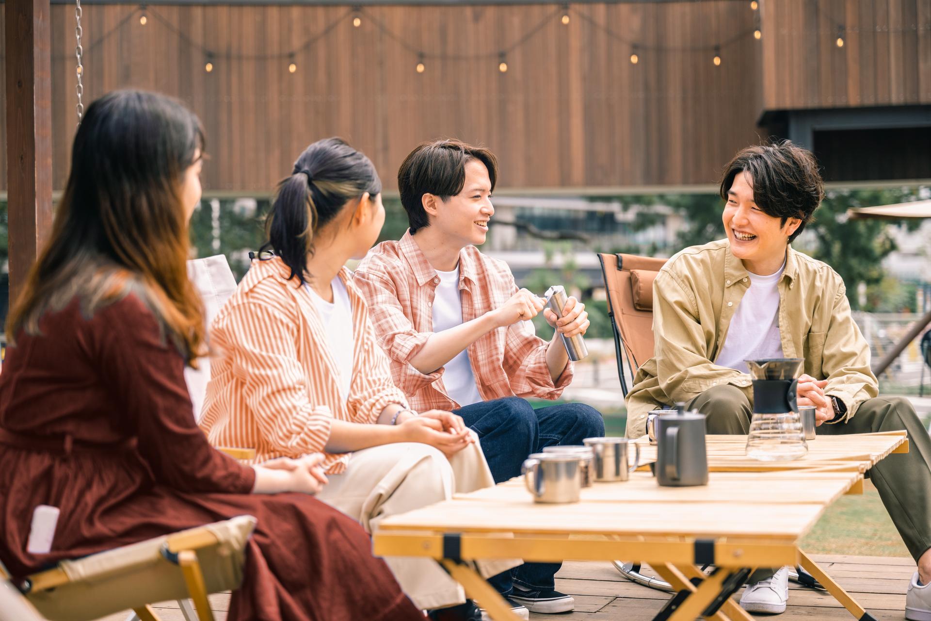 Group_of_friends_sitting_together_at_a_camp_site_laughing_at_the_park.jpg